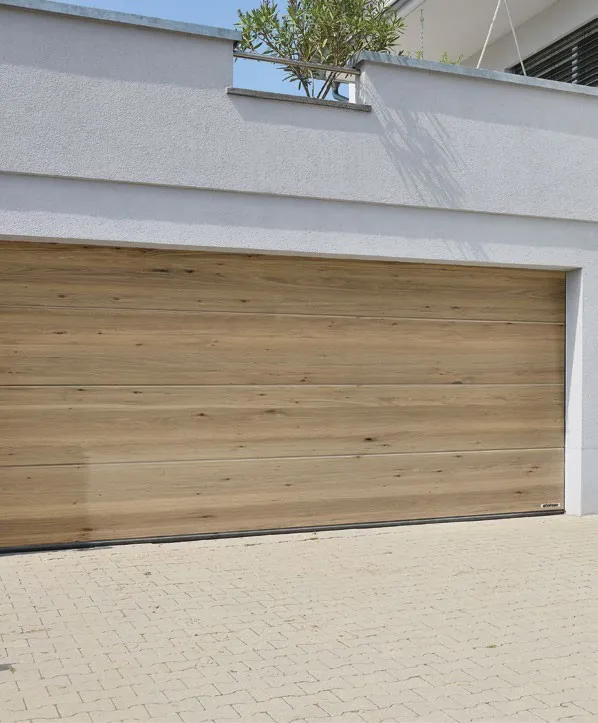 Breites Sektionaltor in Holz-Optik (Eiche) an heller Garage – Garagentore in Isenbüttel von REIMANN