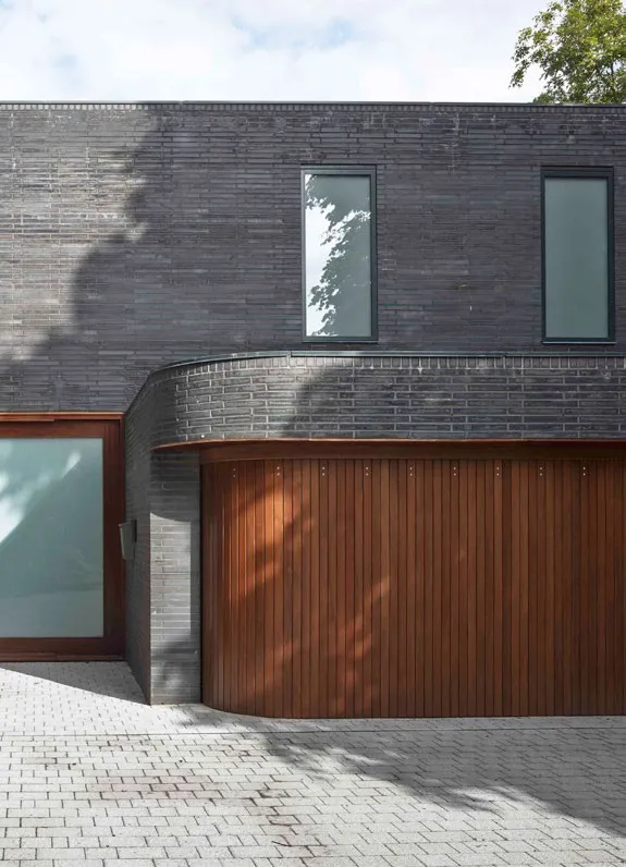 Architektenhaus mit dunklem Klinker und geschwungenem Holz-Garagentor – Garagentore in Braunschweig von REIMANN