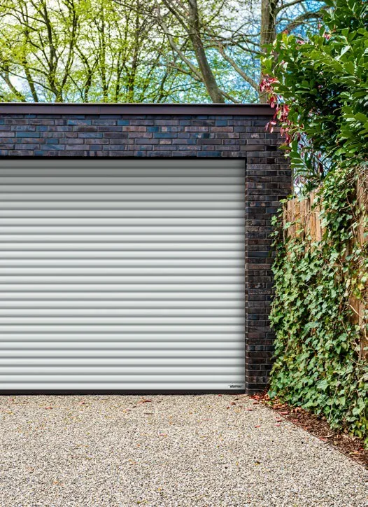 Weisses Rolltor in Klinkergarage mit Efeu-Hecke und Kiesauffahrt – Garagentore in Brome von REIMANN
